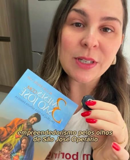 Carla segurando o livro de reflexões sobre São José Operário
